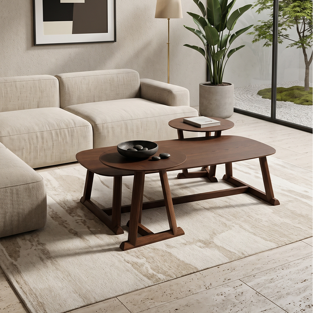 A modern living room scene featuring a dark brown wooden coffee table in the foreground, a matching smaller side table behind it, a cream upholstered sofa, a tall floor lamp, and a large potted plant near a glass wall.